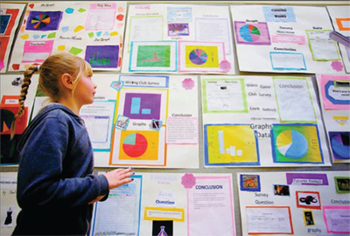 Third-grader Megan Limburg talks about her winning poster (top center) in the statistics poster competition at Jefferson Elementary School in Pullman, Washington. Photo by Geoff Crimmins