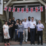 Staff members of the Royal Statistical Society stand in front of their offices on Errol Street in London, England, to celebrate the Queen’s Jubilee Anniversary. From left: Teresa Dewane, Nicola Emmerson, Jack Beeby, Mawreen Chapman, Toni Young, Anna Mair, Charlotte Stovell, Andrew Garratt, Abdel Khairoun, Roeland Beerten, and Paul Gentry  