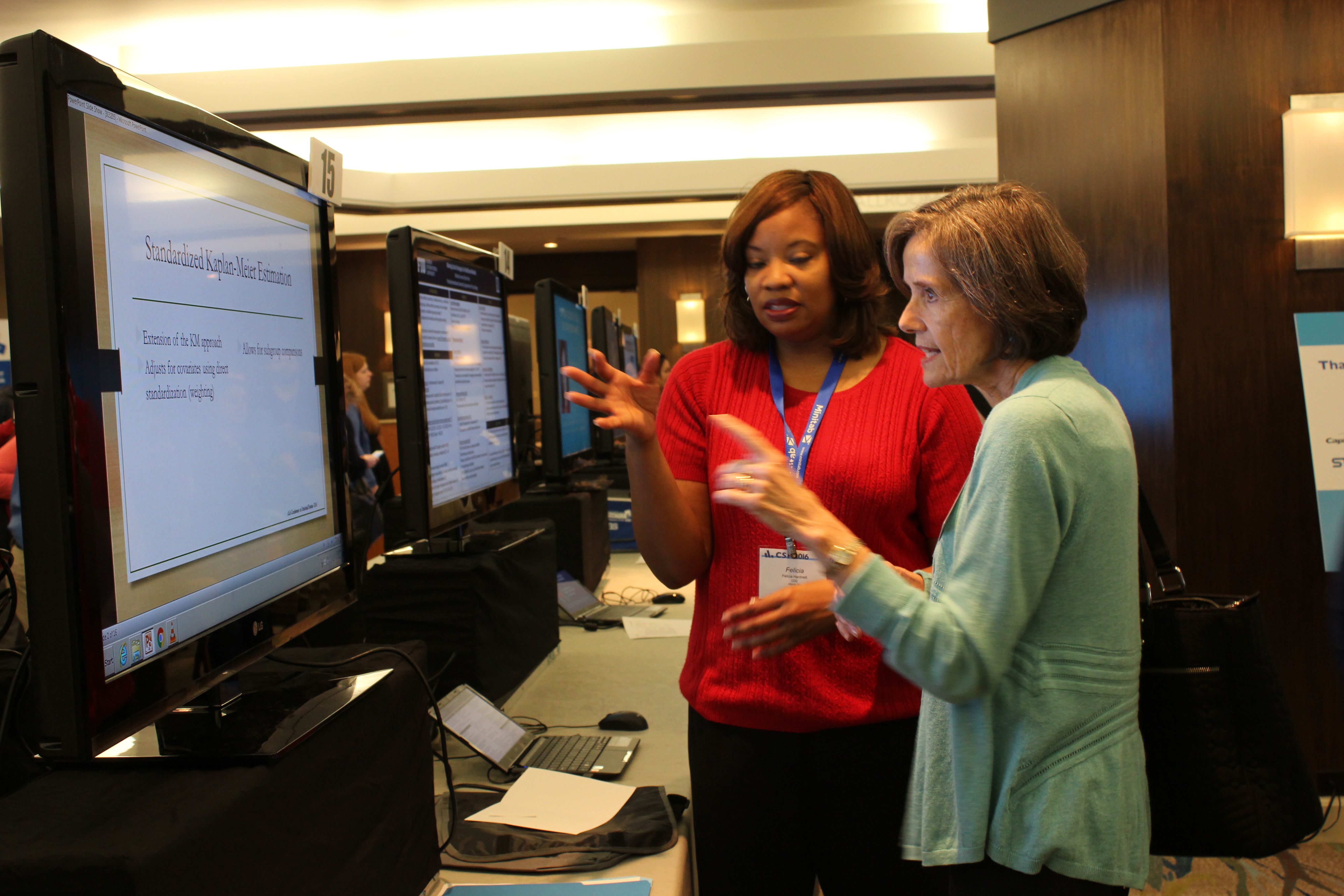Gail Walker listens as Felicia Hardnett of the CDC discusses her poster, which focuses on three classes of statistical methods for comparing survival after AIDS diagnosis across population subgroups.