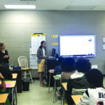 Dale Bowman (left), who led the program, watches Yu Jiang speak in front of high-school students during the West Tennessee Chapter Bring a Student to Work Day.