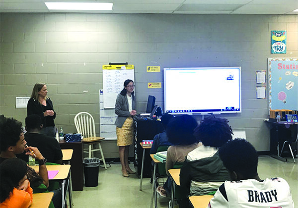 Dale Bowman (left), who led the program, watches Yu Jiang speak in front of high-school students during the West Tennessee Chapter Bring a Student to Work Day.