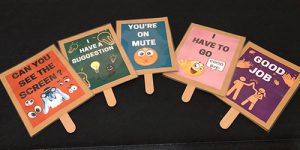 A photo of cards made to use on Zoom. From left, they read “can you see the screen” with a person using binoculars surrounded by eyes; “I have a question” with lightbulb emojis; “you’re on mute” with an emoji with an X for a mouth; “I have to go” with an emoji waving goodbye; and “good job” with two figures giving each other high fives and hand emojis.