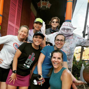 Six people stand around an image of a seventh person. The six people are all in running gear and smiling.