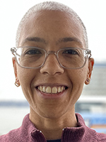 A headshot of a Black woman wearing glasses and smiling