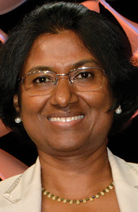 An Indian woman wearing glasses with a bob smiles.