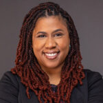 Photo of Stephanie Cook, smiling, long dark curly hair.