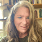 Long hair, slight smile, books in background