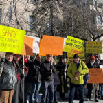 Photo of a group of people holding signs supporting Andreas Georgiou on a DC street.
