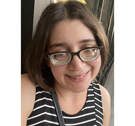 Photo of Erin wearing glasses, wry smile, striped, sleeveless shirt. Shoulder length hair.