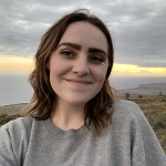 Photo of Sarah smiling with lips closed, sunset in background