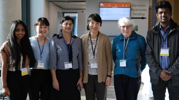 Six people pose and smile. Left to right, there is are four Asian women, a white woman, and a south Asian man.