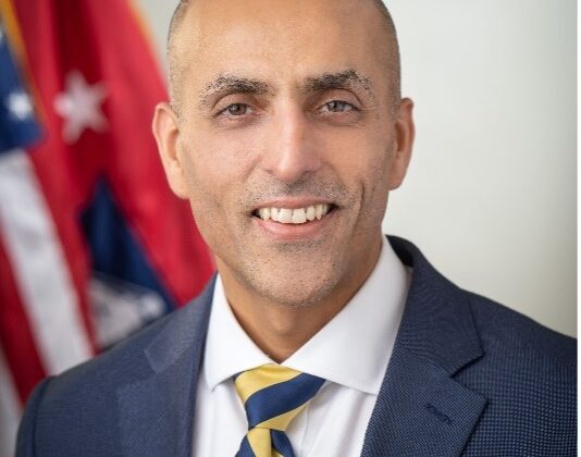 Photo of Vipin Arora, striped tie, dark suit, large smile.