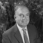 Black and white photo of Chris Barker, suit and tie, slight smile.