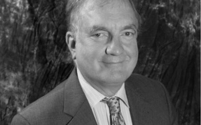 Black and white photo of Chris Barker, suit and tie, slight smile.