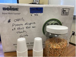 Jar of beans in foreground, with styrofoam cups and a sign behind it that reads "Chris, Please dispose of this for me. Thanks, Golde.