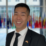 Photo of Nathen Huang, wearing suit and tie, smiling.