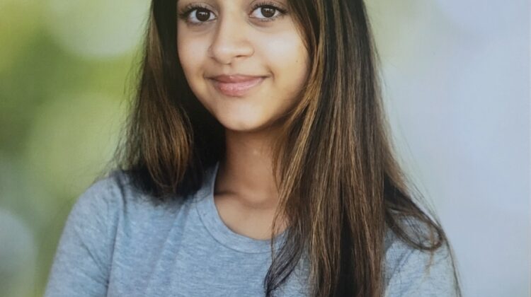 Photo of Jaya Kolluri. She is wearing a t-shirt has very long hair, slight smile