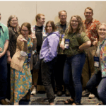 A photo of 13 members of the USCOTS Program Committee, all cheering