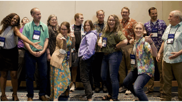 A photo of 13 members of the USCOTS Program Committee, all cheering