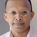 A Black man with frameless glasses and short hair