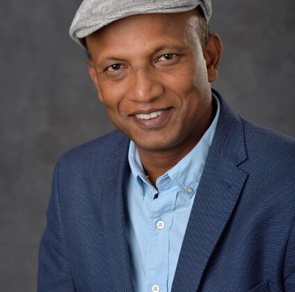 Tapabrata (Taps) Maiti wearing a hat, button down shirt, and jacket.