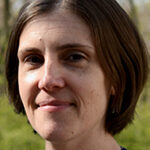 A white woman with short straight brown hair smiles slightly