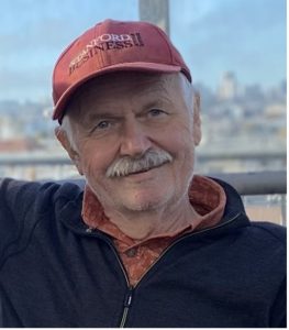 Photo of Ledolter, gray mustache, slight smile, baseball cap