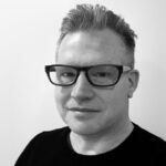 Black and white headshot of Zink. Glasses, short hair