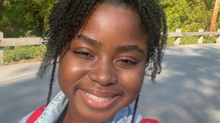 A young black woman with her hair pulled back smiles widely