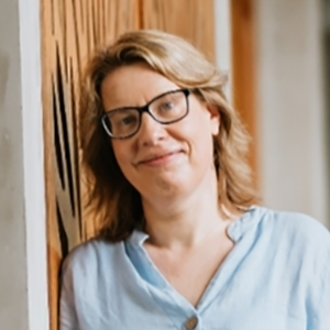 Portrait of Aurore Delaigle, a white woman with blond shoulder-length hair, brown rim glasses, and a slight smile