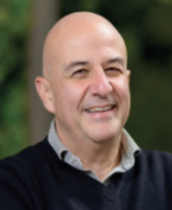 Bald, smiling, collared shirt under sweater