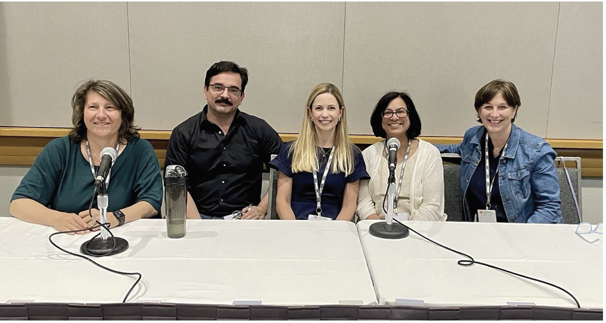 Five people sitting in front of a table with microphones in front of their faces