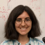 Portrait of Tamara Broderick, a woman with dark shoulder-length hair, glasses, and a big smile