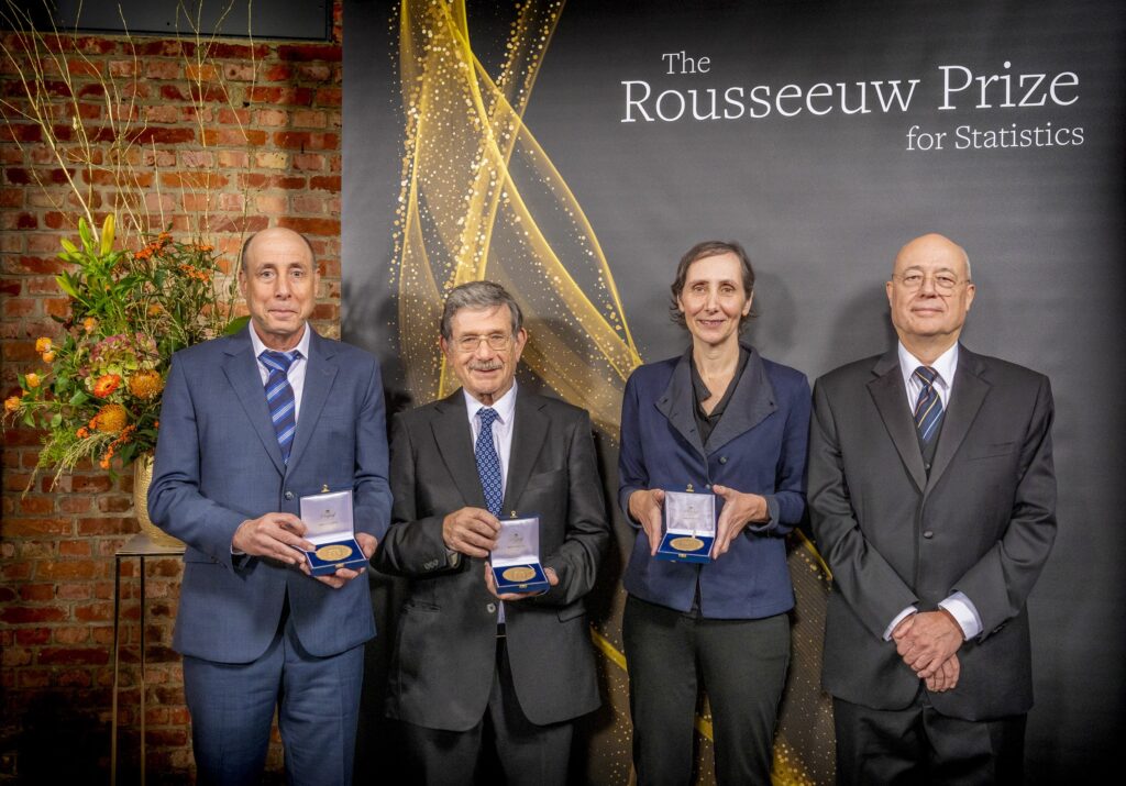 Photo of From left: Daniel Yekutieli, Yaov Benjamini, and Ruth Heller holding their prizes, and Peter Rousseeuw; all are wearing black or blue business suits.