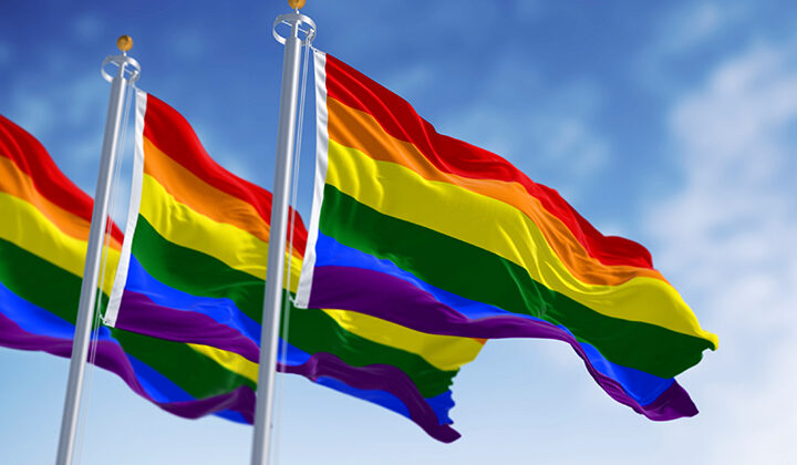 Rainbow flag waving on a clear day. Multicolored flag with stripes in the colors of the rainbow, often used as a symbol of LGBT pride. 3d illustration render. Fluttering fabric