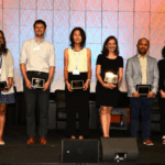 A group of people in a conference center ballroom holding plaques