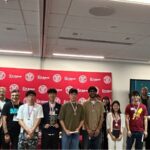 a group of people standing in front of a red backdrop wearing medals