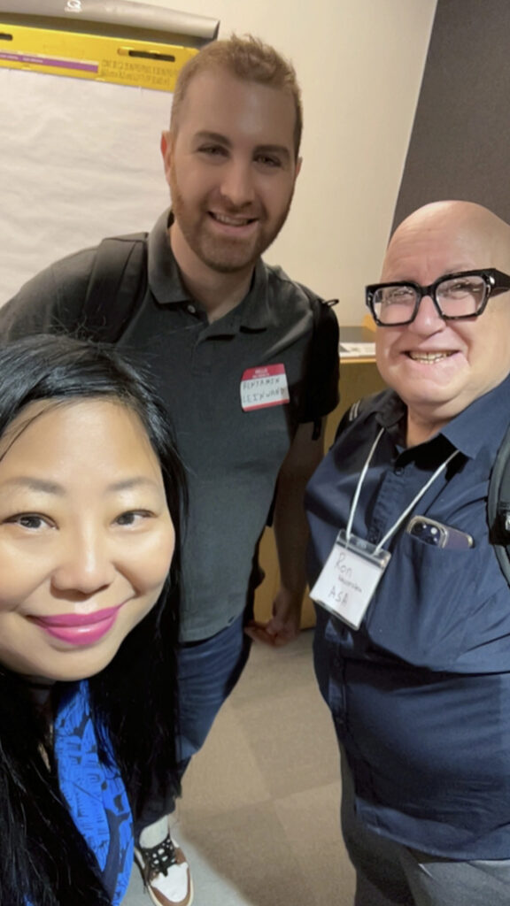 An Asian woman with two men smile