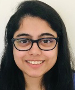 A woman with long dark hair and dark glasses and brown eyes smiles