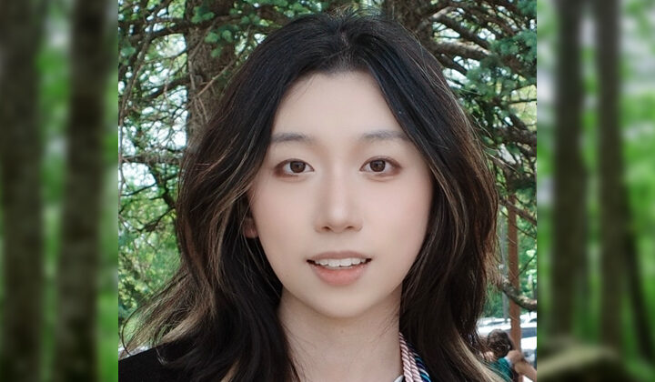 Leah Qin's headshot - smiling with long, dark, wavy hair