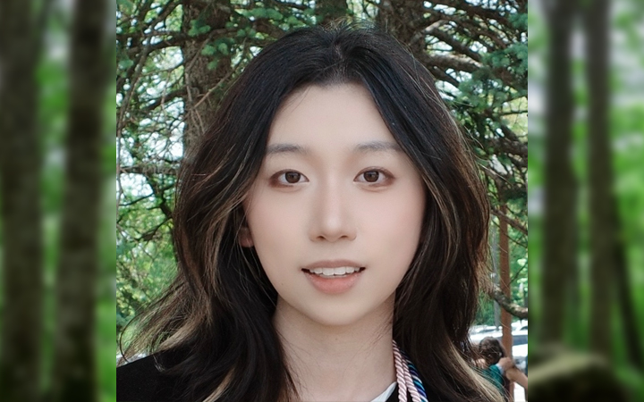 Leah Qin's headshot - smiling with long, dark, wavy hair