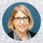 Marcia Levenstein's headshot. She is wearing black-rimmed glasses, a black sweater, and a black and white patterned shirt and has a blonde bob haircut.