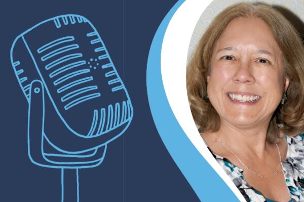Jeri Mulrow smiling at the camera - shoulder-length blonde hair and a black, white, and blue floral blouse. She is next to an illustration of a microphone.