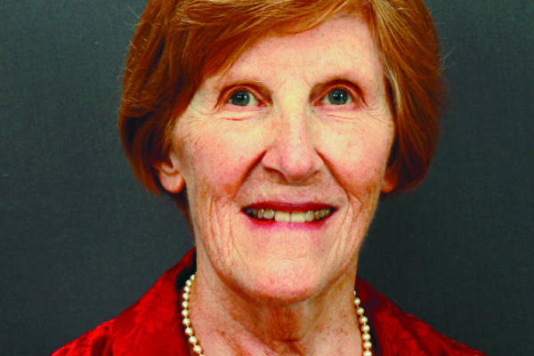 Short hair, big smile, wearing pearl necklace and v-neck blouse