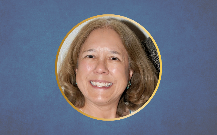 A white woman with brown hair smiles widely in a circle on a blue background
