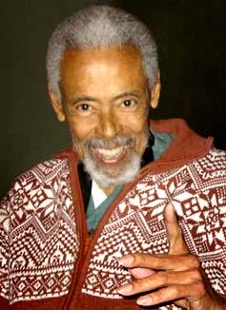 Charles Bernard Bell Jr. smiles at the camera, with short gray hair and a brown and white patterned sweater.