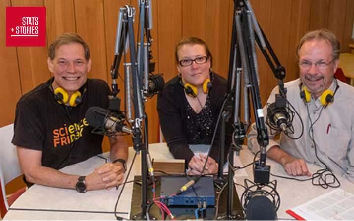 John (short hair, big smile) Rosemary, (hair pinned back, slight smile) and Richard Cambell (mustach and beard, big smile) sit around a desk with microphones in front of them