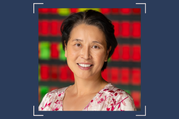 An Asian woman in a floral shirt in front of a red and green background