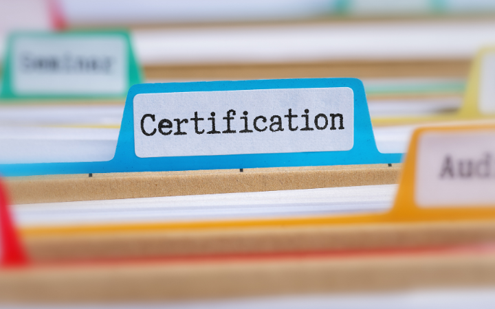 multiple file folders. The centered file has certification typed on it