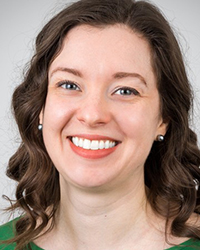 A white woman with wavy brown hair smiles